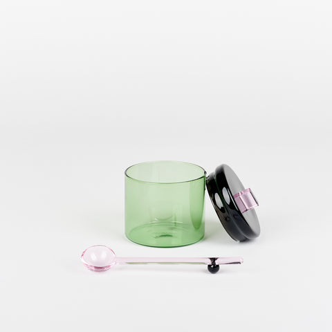 an Areaware Sophie Lou Jacobsen small green glass sugar bowl with a black lid and a small pink glass spoon beside it