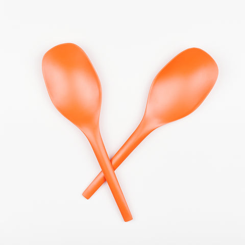 a pair of orange colored minimalist serving spoons made out of bamboo