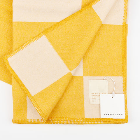Detail view of the texture and edges of Manifatura wool throw blanket in Aspen color style showing the tag on the blanket