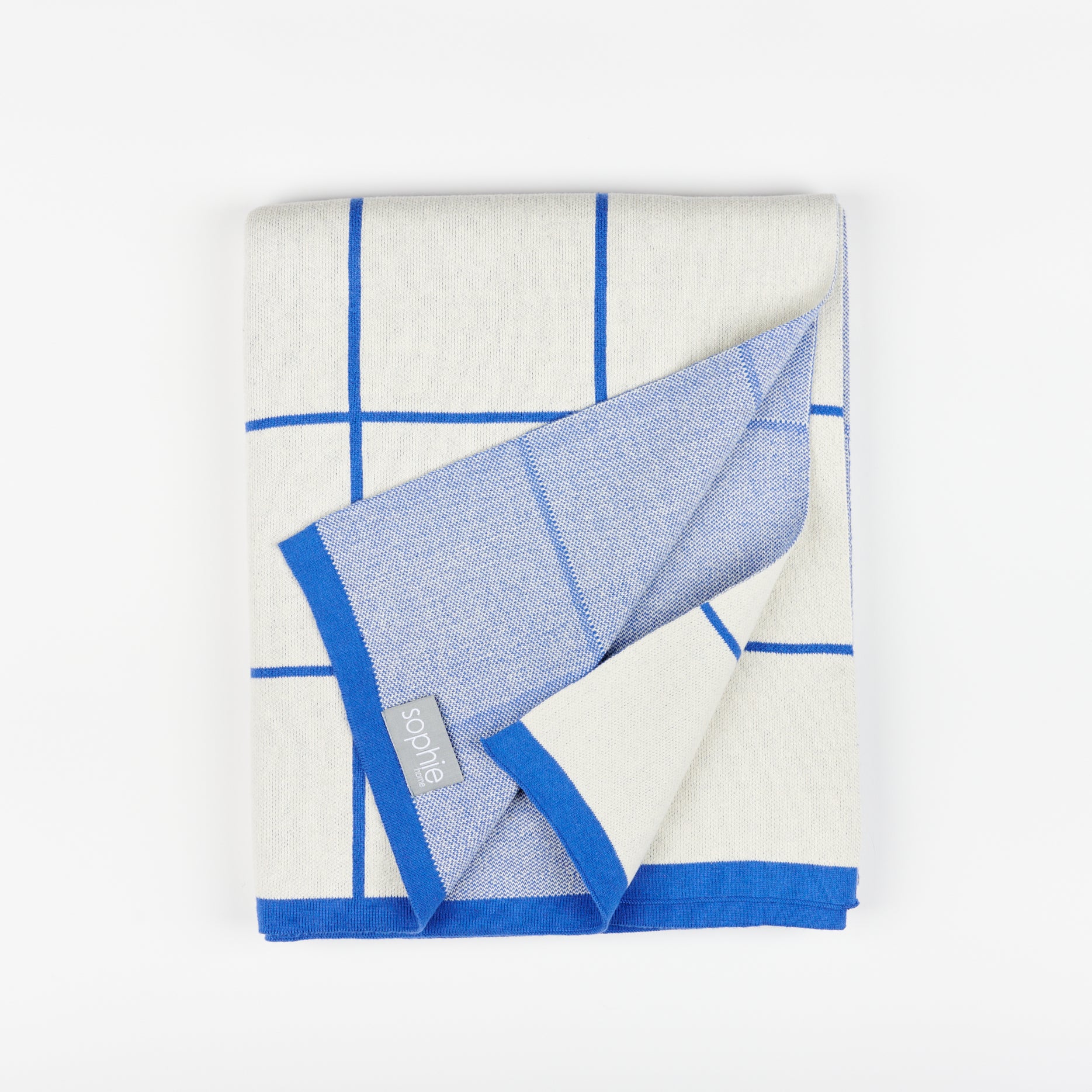 Sophie Home grid cotton knit throw blanket in cobalt with corner lifted to show tag and underside of the blanket