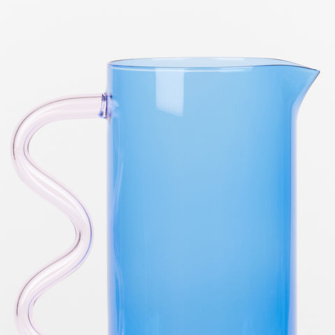 a close up of a blue glass pitcher with a pink wavy glass handle