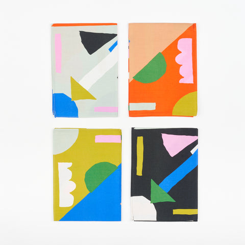 four folded napkins with alternating designs that feature an array of colorful shapes that look like arrows and clouds