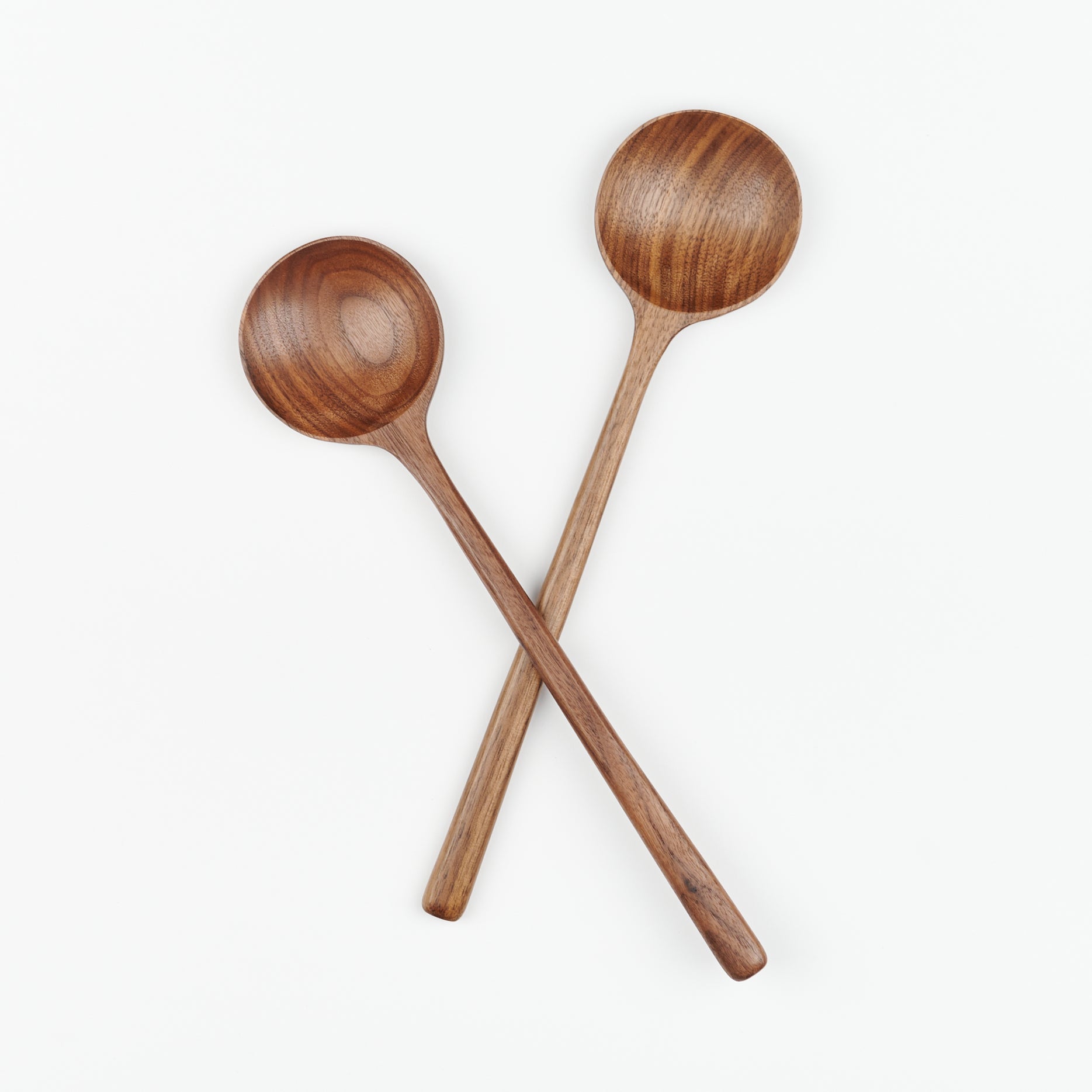 A pair of walnut spoons by JBrody&Co laying in an x shape