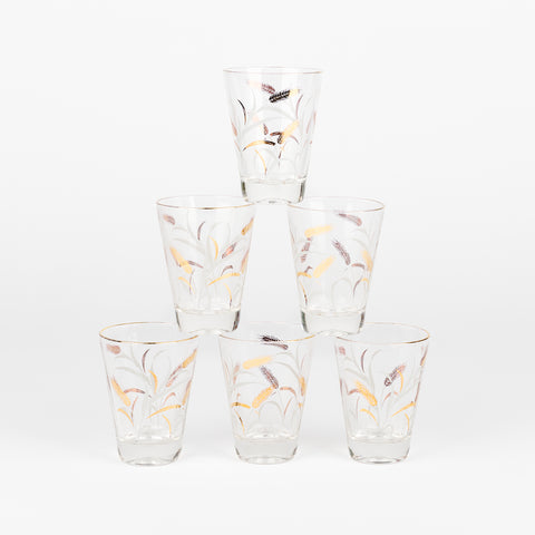 stack of six short vintage juice glasses with a decorative golden wheat pattern