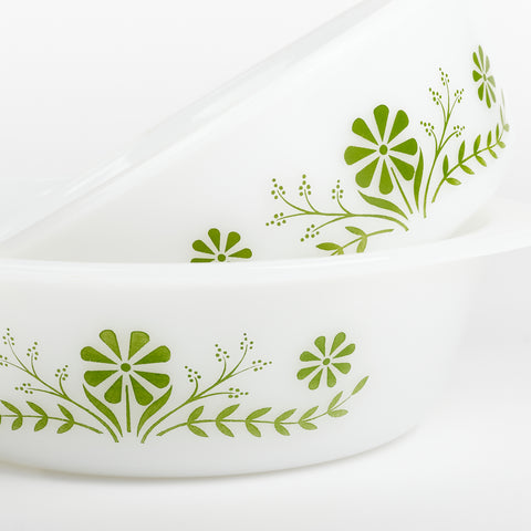 A closeup view of a green floral design on the side of two white glasbake casserole dishes