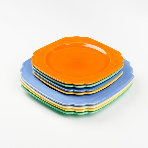 a stack of eight Riviera Ware plates, four small and four large all in different colors