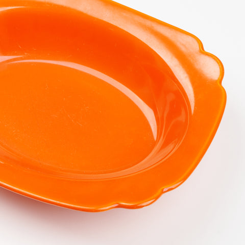 a close of the curved edges of a red Riviera Ware serving bowl