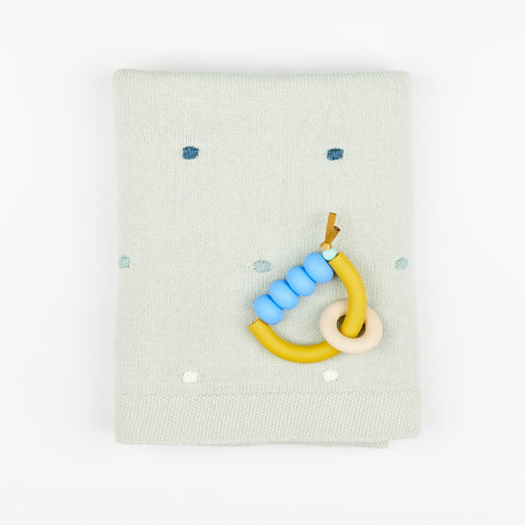 folded mint green baby blanket with decorative polka dot accents and a color coordinating teething ring for enfants