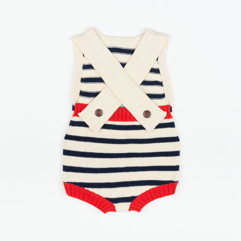 The back of a knitted cream and navy striped baby romper with red accents and wooden buttons for attaching straps