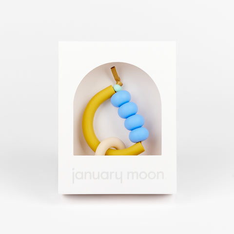 A non-toxic pastel baby teething ring in a white box made by January Moon