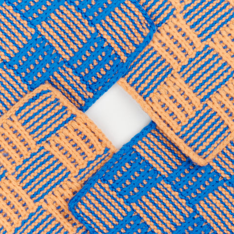 close up view of Verloop Checkerboard knit coaster with an intricate woven pattern in blue and orange