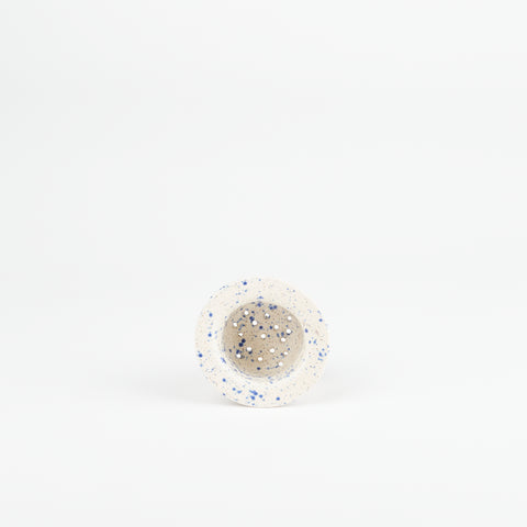 a blue speckle ceramic tea strainer handmade by Utility Objects laying on its side