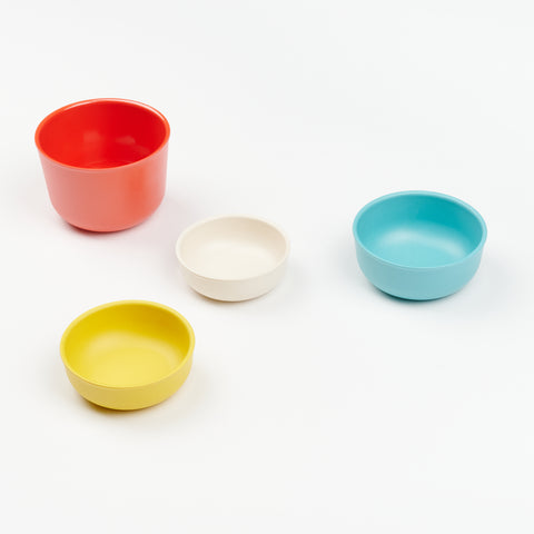 an array of different sizes of bamboo measuring cups in red, blue, yellow, and white