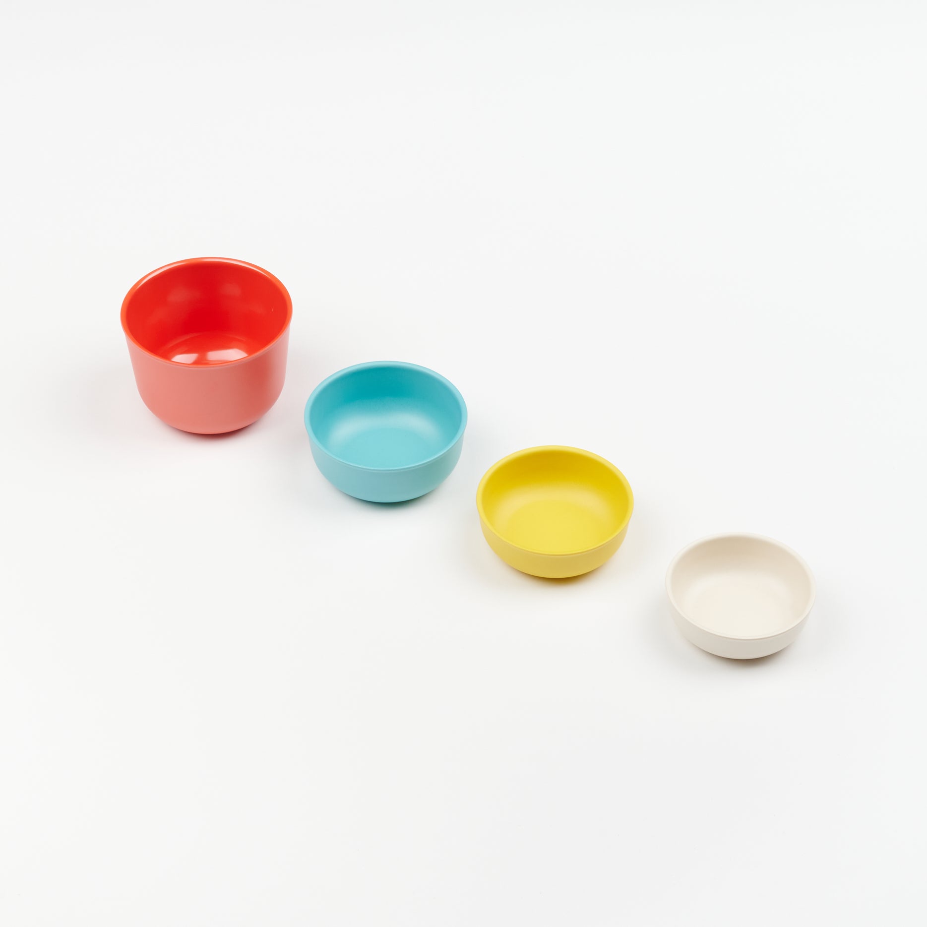 a line of four mult-colored measuring cups from large to small
