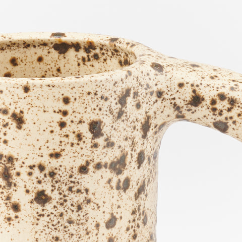 close up of a handmade ceramic mug with a brown speckled eggshell glaze