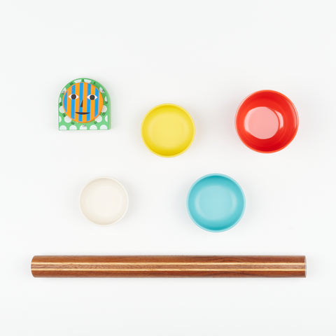  A handmade rolling pin, four colorful bamboo Ekobo measuring cups, and an Areaware Kitchen Timer arranged artfully on a white backdrop