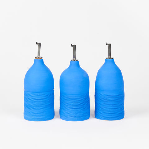 three cobalt blue ceramic oil cruets each with slight variations in size and shape