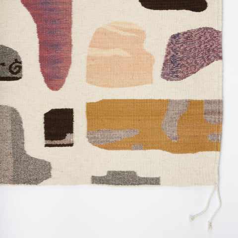 detail of a handwoven rug with a design showing different shapes and sizes of colorful stones