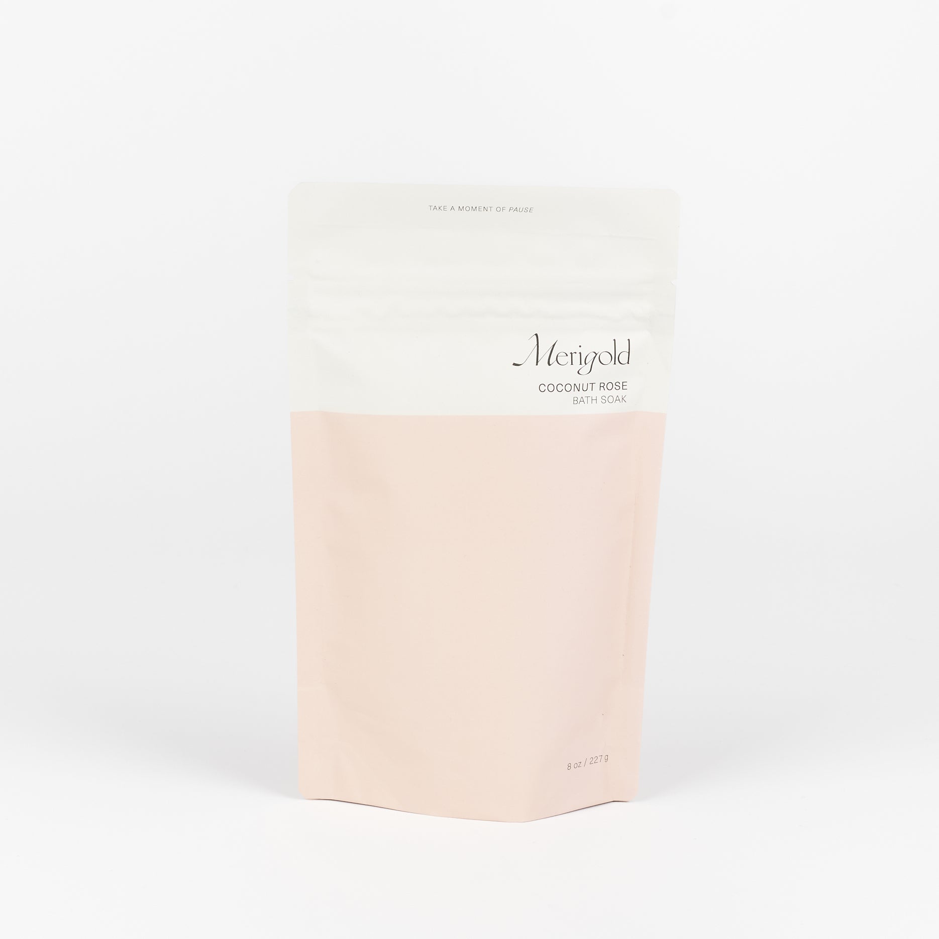 A pink and white bag of Merigold Coconut Rose Bath Soak with the phrase Take A Moment To Pause on it