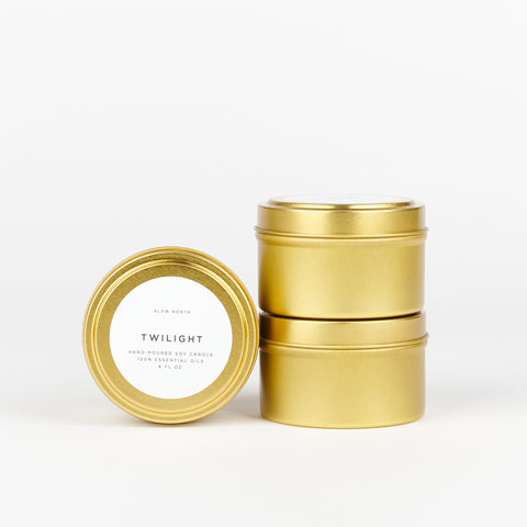 three tin soy wax candles by Slow North one turned on its side showing the scent - Twilight