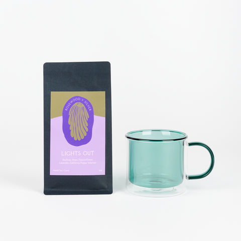 A Poketo Double Wall Mug in Teal next to a black bag of Rosewood + Silver Tea called Lights Out with a lavender and ochre label