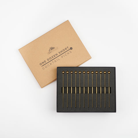 A Bar Above gold cocktail picks inside of their open box