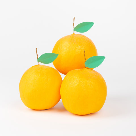 A bunch of TOPS Malibu Surprise balls that are in the shape of oranges with a green paper leaf