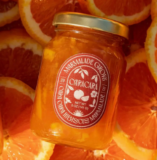 Jar of caracara orange marmalade sitting on a background of flat cut orange slices