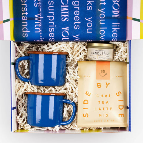Kindled Comfort gift box with Side by Side Chai, blue enamelware mugs, and Candlefish travel tin candle.