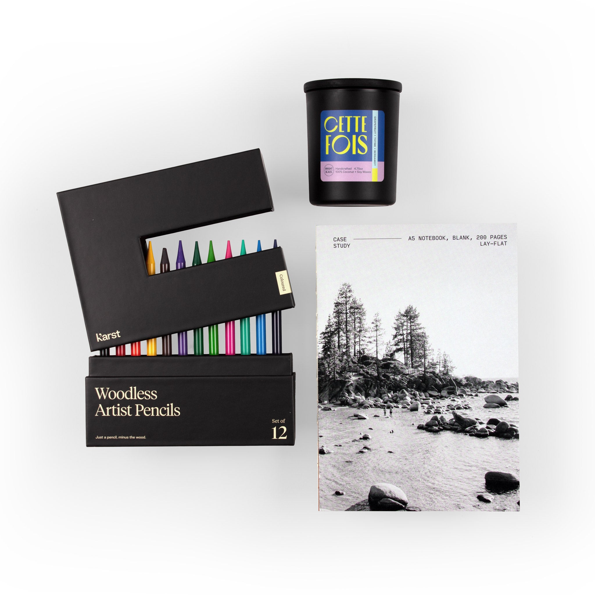 Overhead view of the True Colors gift set featuring a blank Case Study notebook, a CETTE Fois candle, and Karst woodless artist pencils with the back box partially open to reveal an array of colorful pencils.