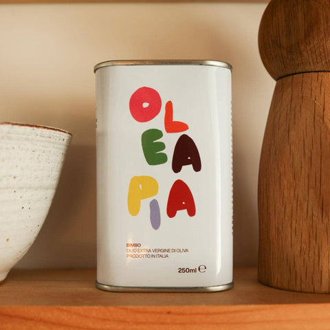 Olea Pia extra virgin olive oil tin displayed on wooden shelf, included in the Form and Flavor gift set.