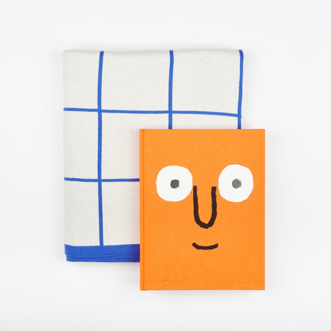 A Book and Blanket Gift set including Phaidon design book Jean Jullien and a Sophie Home Cotton Knit Throw blanket with a cobalt blue grid