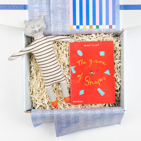 A Cette gift box showing a plush stuffed animal cat in in stripes and Phaidon Kids book The Game of Shapes by Herve Tullet