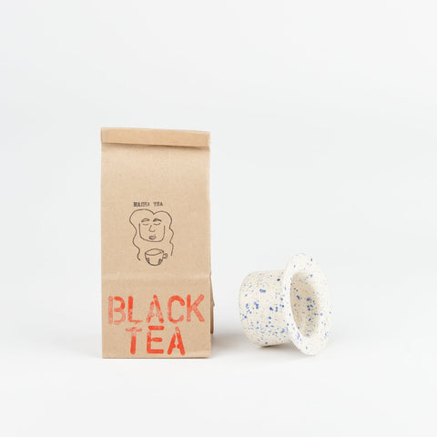 A Utility Objects blue speckle ceramic tea strainer and a bag of Masha Tea loose leaf Black Tea