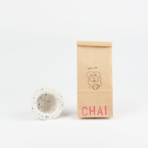 A Utility Objects blue speckle ceramic tea strainer and a bag of Masha Tea loose leaf Chai Tea