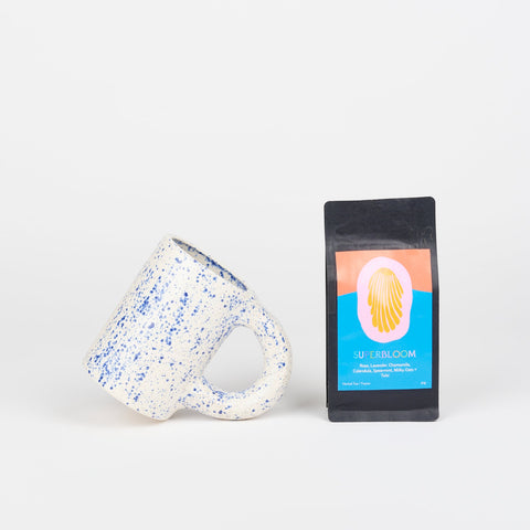 A Utility Objects Nagai ceramic mug in speckled blue and a bag of Superbloom Rosewood and Silver loose leaf tea 