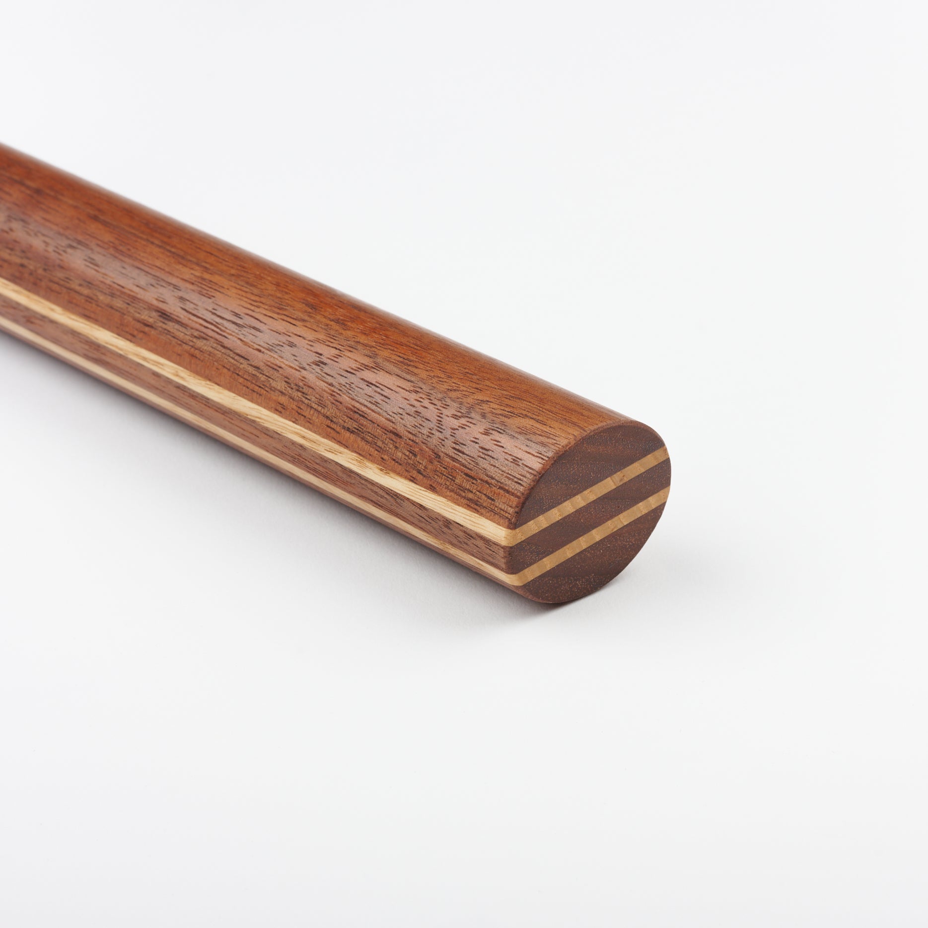 Close up view of the end of a limited edition hand turned wooden rolling pin with inlaid double stripe lines